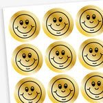 A sheet of metallic gold stickers each with a smiling face as a black outline as it's design