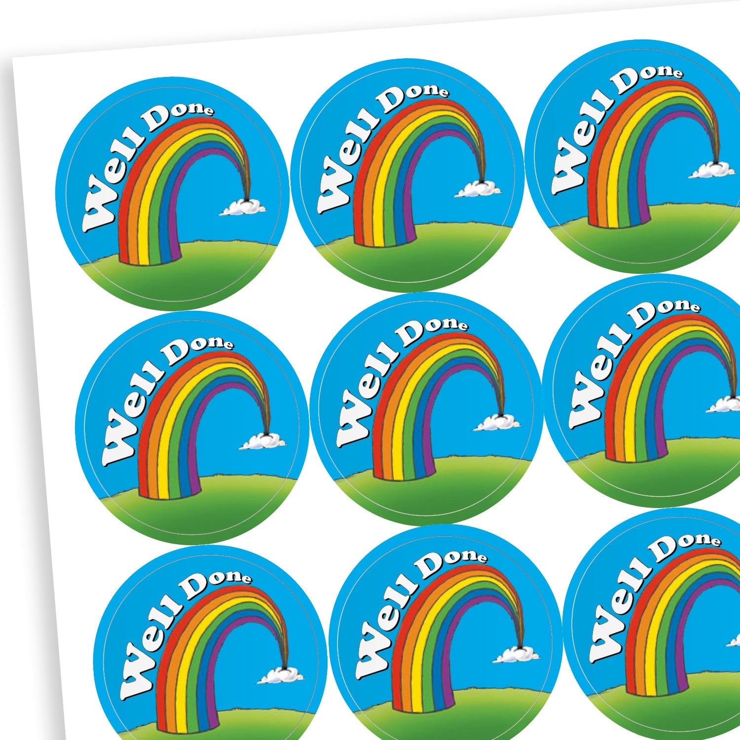 A sheet of circular reward stickers. Each sticker features a colourful rainbow arcing from grassy hills toward small clouds, set against a bright blue sky. The words 'Well Done' are written in bold white text along the curve of the rainbow.