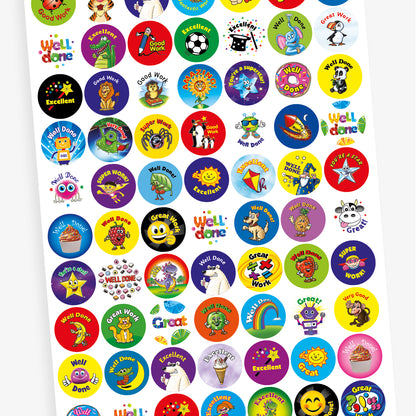A sheet of colourful circular reward stickers featuring cheerful characters and motivational phrases such as 'Good Work', 'Amazing', 'You're a Superstar', 'Super Work', 'Well Done', and 'Excellent'. Designs include an owl, sunflower, spider, penguins, a robot with sunglasses, a ladybird, a smiling sun, and a kite, each set against vibrant backgrounds to encourage positive behaviour and achievement