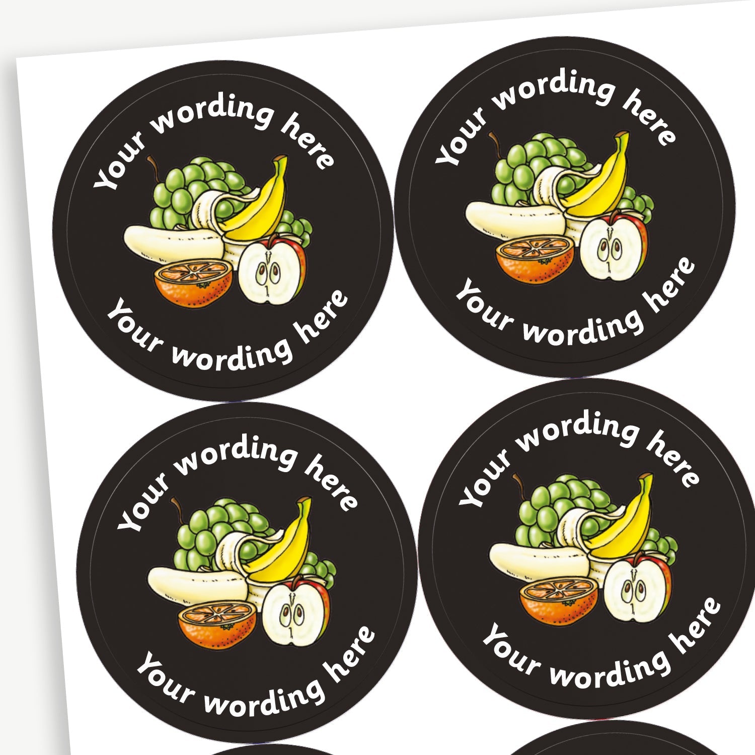 A sheet of circular stickers with a black background. Each sticker features a selection of fruit as a central image including a bunch of grapes, a peeled banana and half an apple and orange. The placeholder 'Your wording here' is written in white font above and below the image.