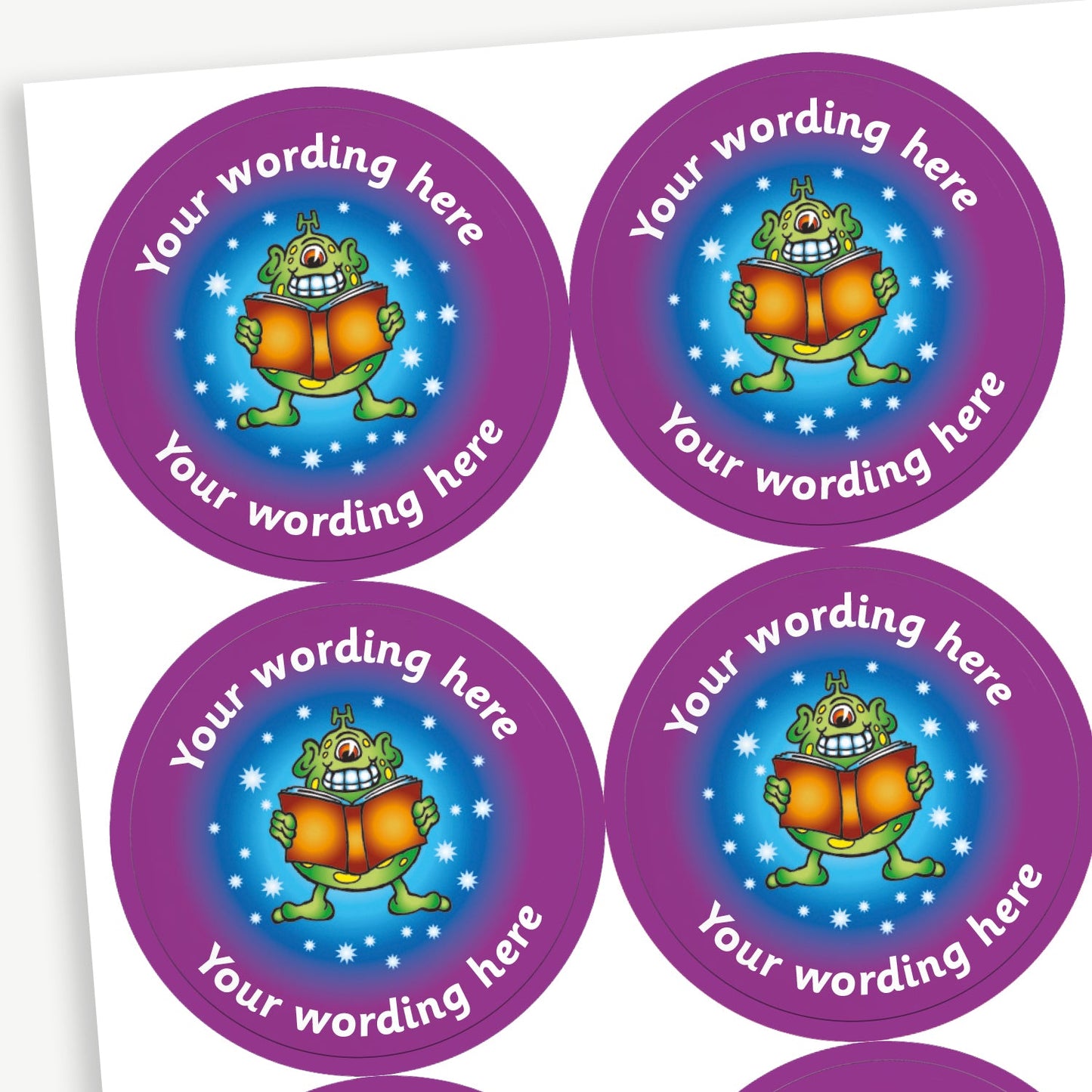 Sheet of round stickers with a purple border and featuring an alien reading a book against a blue starry background in the centre. Each sticker has placeholder text reading 'Your wording here' curved above and below the illustration. 