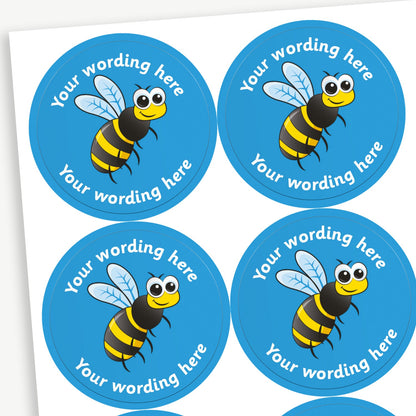 Sheet of round blue stickers featuring an cartoon bee in the centre. Each sticker has placeholder text reading 'Your wording here' curved above and below the illustration. 