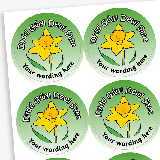 A sheet of green stickers featuring a daffodil in the centre.  Wording 'Dydd Gwyl Dewi Sant' is above the image. Placeholder text 'Your wording here' is below the image for customisation.