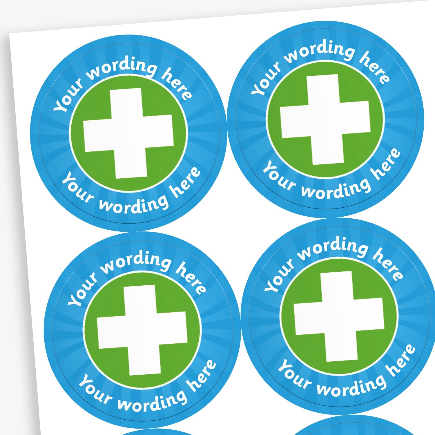 A sheet of customisable circular stickers featuring a cyan border and a green centre with a white first aid cross on it; includes customisable text above and below the image.