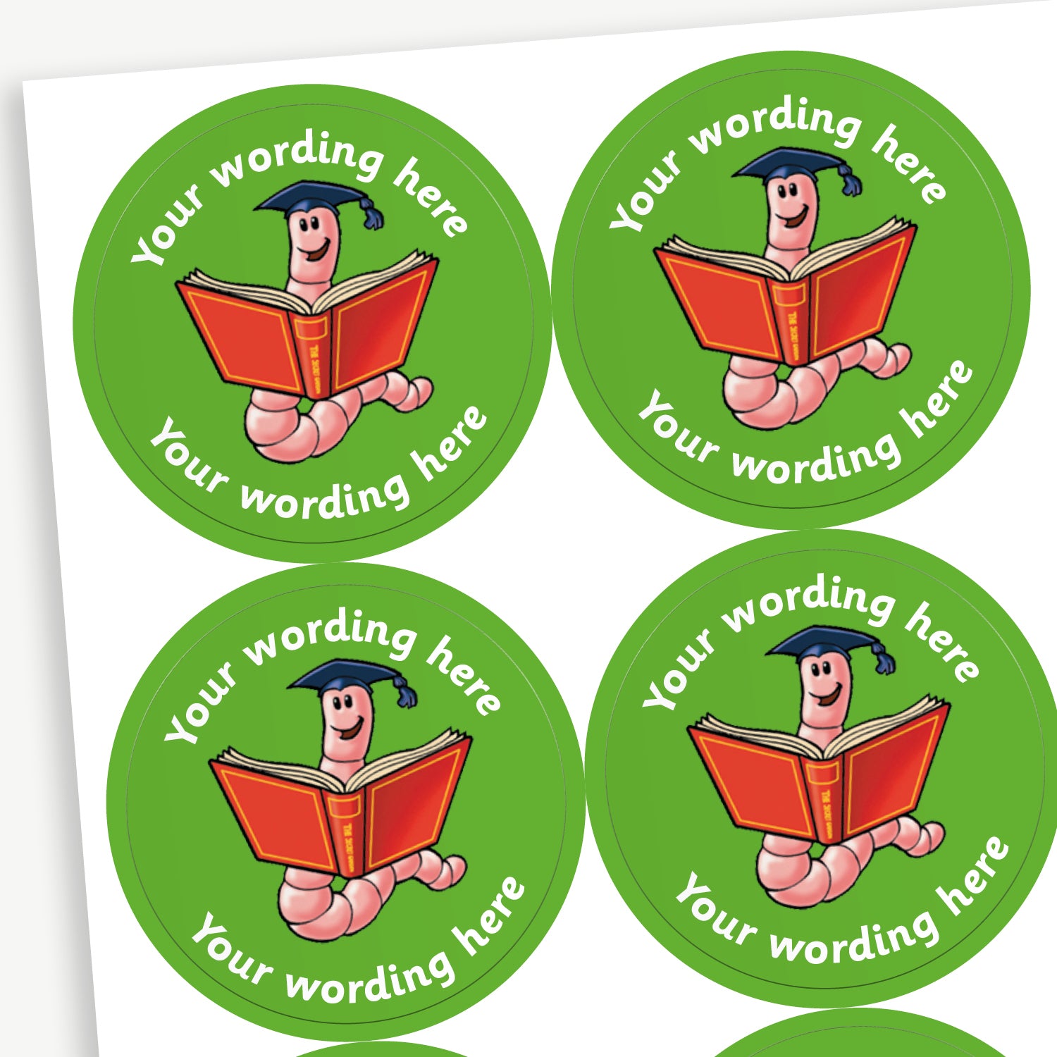 Sheet of round green stickers featuring a smiling cartoon bookworm wearing a graduation cap and holding an open red book. Each sticker includes placeholder text reading 'Your wording here' curved above and below the illustration. 