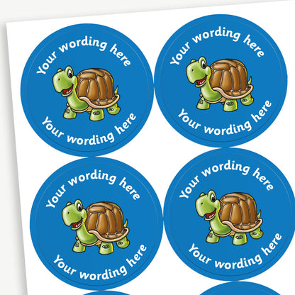 A sheet of blue circular stickers featuring a cartoon tortoise in the centre; curving above and below the image is space for personalisation 'Your wording here' in a clear, bold font.