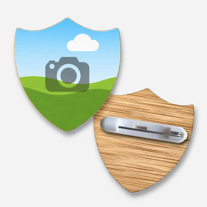 Front and back view of a customisable shield-shaped bamboo badge. The reverse features a plastic safety pin fastening attached to the wood-textured surface.