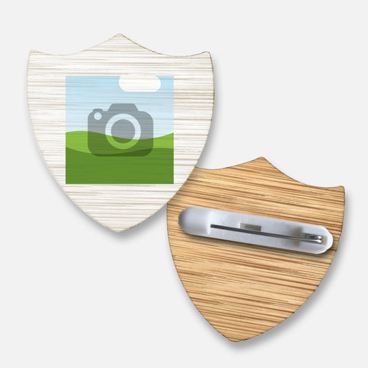 Front and back view of a customisable shield-shaped bamboo badge . The front displays a square image placeholder for personalisation, while the reverse features a metal safety pin fastening attached to the wood-textured surface.
