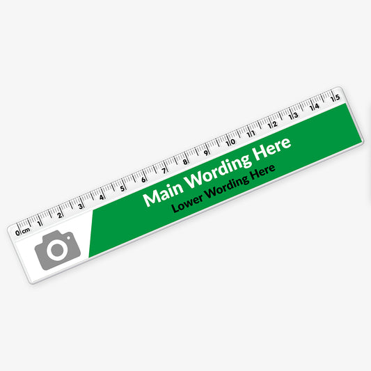 Customisable plastic ruler with a green and white design. It includes placeholder text reading 'Main Wording Here' and 'Lower Wording Here' in bold and regular fonts. A grey camera icon marks the area for a potential logo or image. The ruler is marked with centimetres and millimetres from 0 to 15.