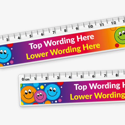 Close up of 15cm ruler featuring space in the centre for custom top and bottom wording in bold text, decorated a spectrum of vibrant colours and 3 colourful, smiling cartoon faces at each end.