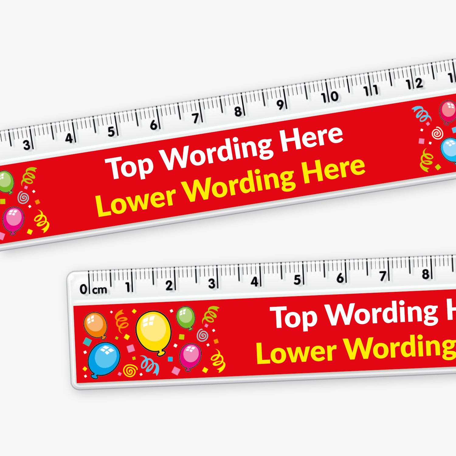 A close up of two 15cm plastic rulers with black measurement markings along the top edge. The design features a bright red background with colourful balloons and confetti. In the centre, large white text reads 'Top Wording Here', with yellow placeholder text below saying 'Lower Line Wording Here'.