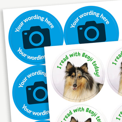 A sheet of circular stickers with a blue background and the centre has a camera icon to indicate customisation.  Placeholder text 'Your wording here' arcs above and below the icon.  In front is an example image with a dog photo uploaded and the text saying 'I read with Benji today!'