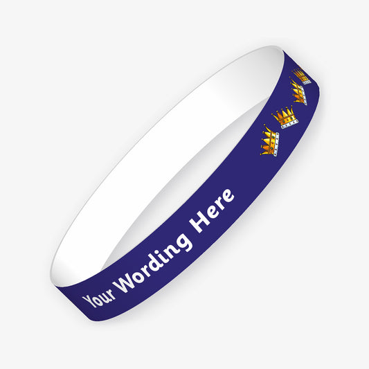 A customisable wristband with a dark blue background and white text.  The centre is displaying the placeholder text 'YOUR WORDING HERE' alongside images of gold crowns on jaunty angles resplendant with jewels.