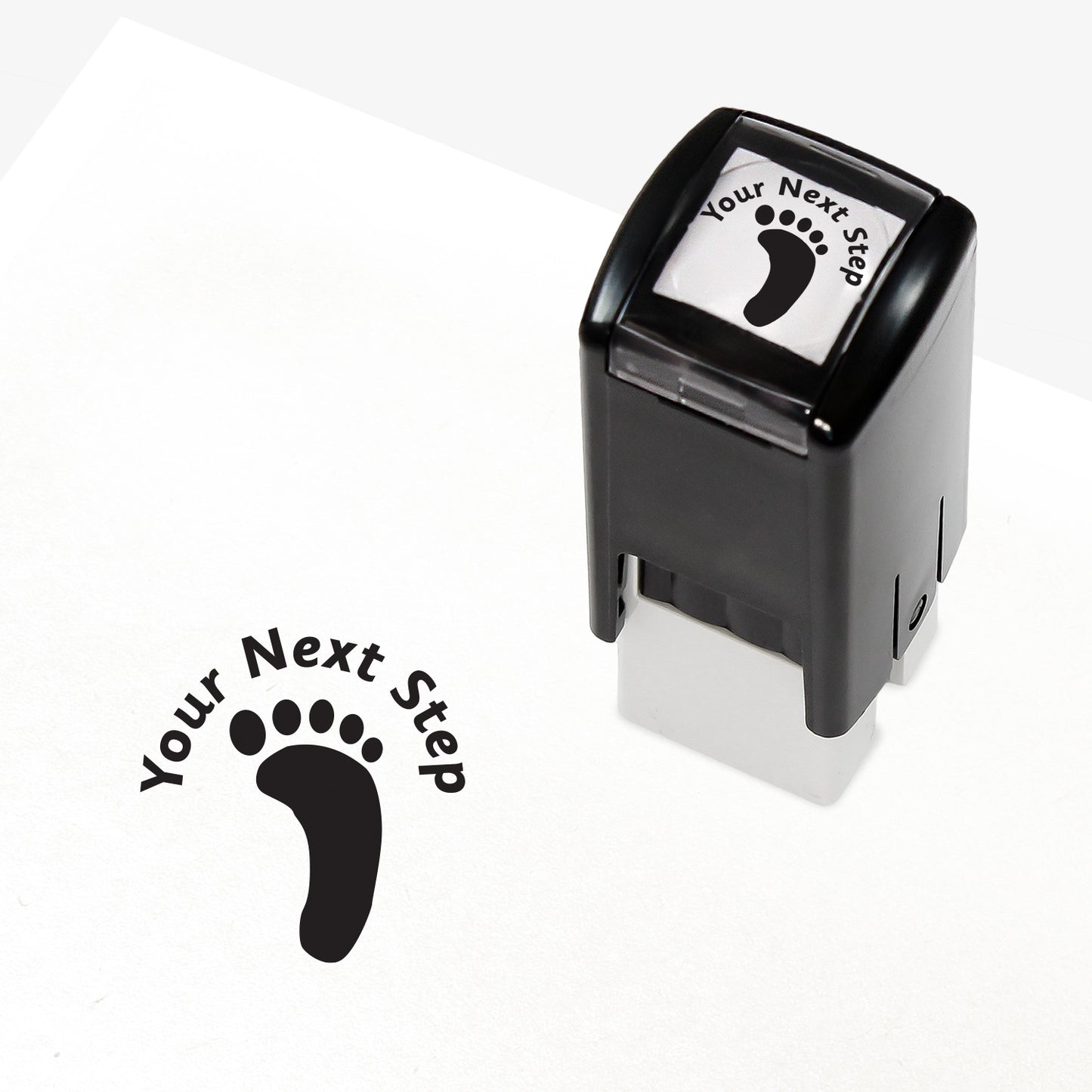 Black 25mm pre-inked stamper featuring a footprint with the phrase 'Your Next Step' above.