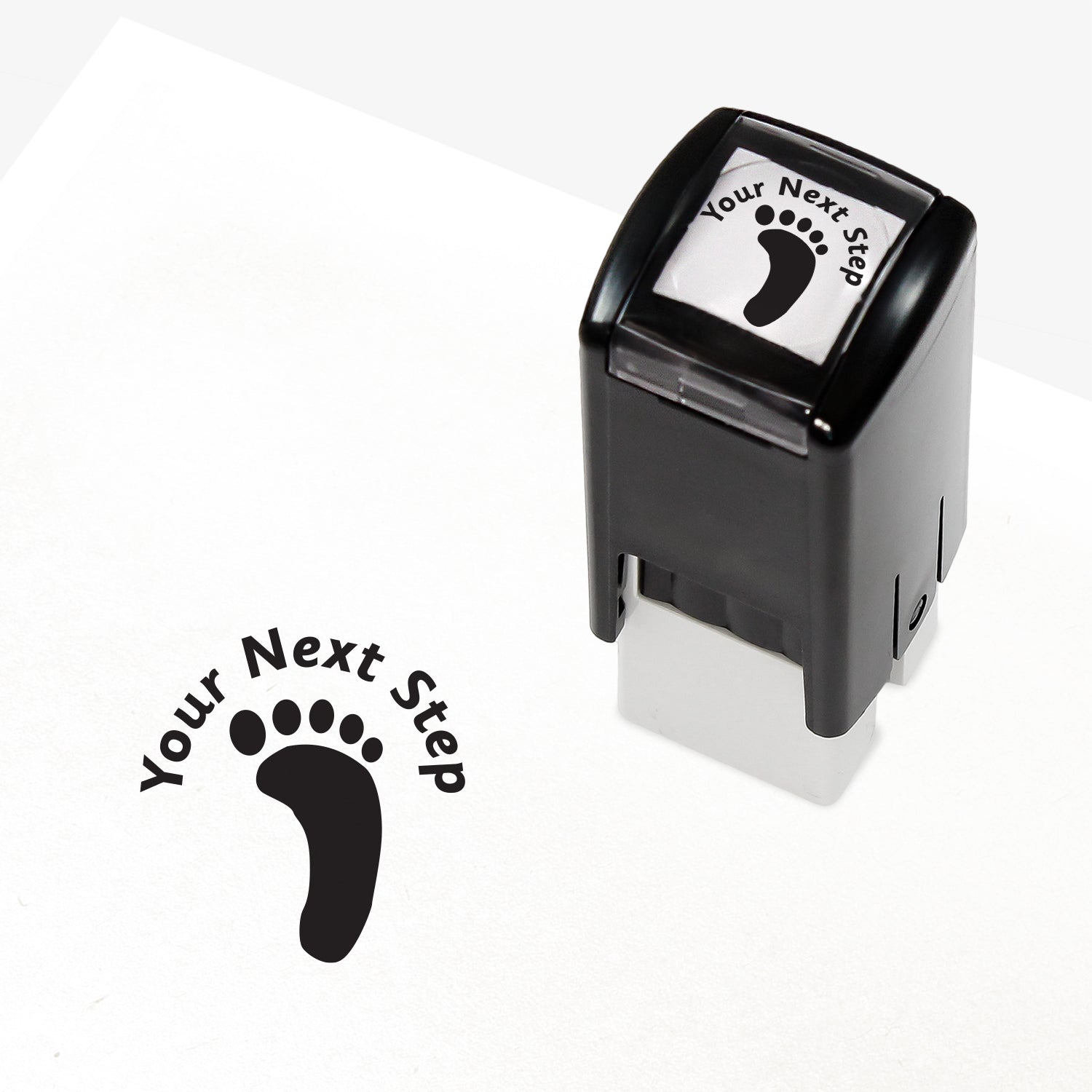 Black 25mm pre-inked stamper featuring a footprint with the phrase 'Your Next Step' above.