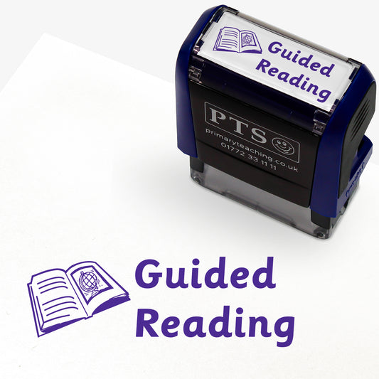 38mm x 15mm self-inking stamper featuring the phrase 'Guided Reading.' in bold purple letters next to an illustration of an open book with lines on one page and a globe on the facing page.