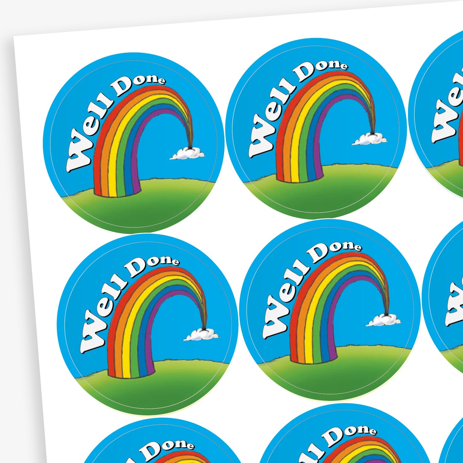 Sheet of round reward stickers featuring a rainbow arching over a green hill with the words 'Well Done' in white on a blue sky background with small clouds.