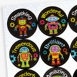 A sheet of circular reward stickers with a black background, each featuring a colourful holographic cartoon robot and positive words such as 'Smashing', 'Wonderful', 'Tremendous', and 'Brilliant'. Surrounding each robot are small, colourful gear icons.