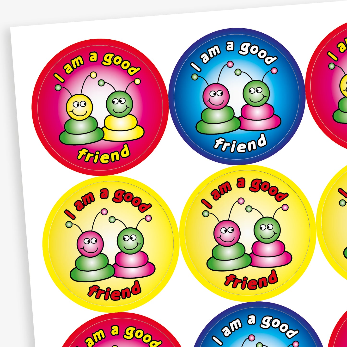 A sheet of round reward stickers in various bright colours, each with the phrase 'I am a good friend' written in bold, playful text. Each sticker features two cartoon alien-like characters with antennae, sitting side by side and smiling. The background colours include red, blue, yellow, and pink gradients, creating a cheerful and encouraging design aimed at promoting positive social behaviour.