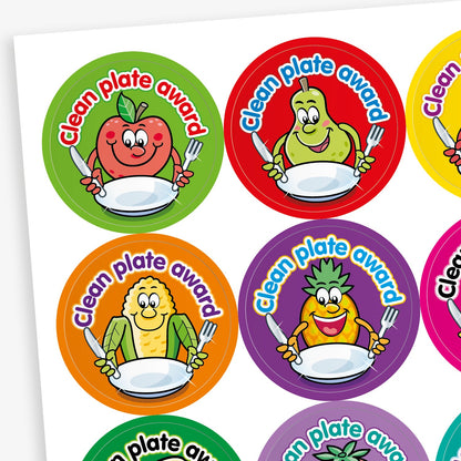A sheet of colourful circular 'Clean Plate Award' stickers featuring smiling cartoon fruits and vegetables, such as an apple, pear, corn, and pineapple, each holding a knife and fork with an empty plate. Background colours include green, red, orange, and purple.