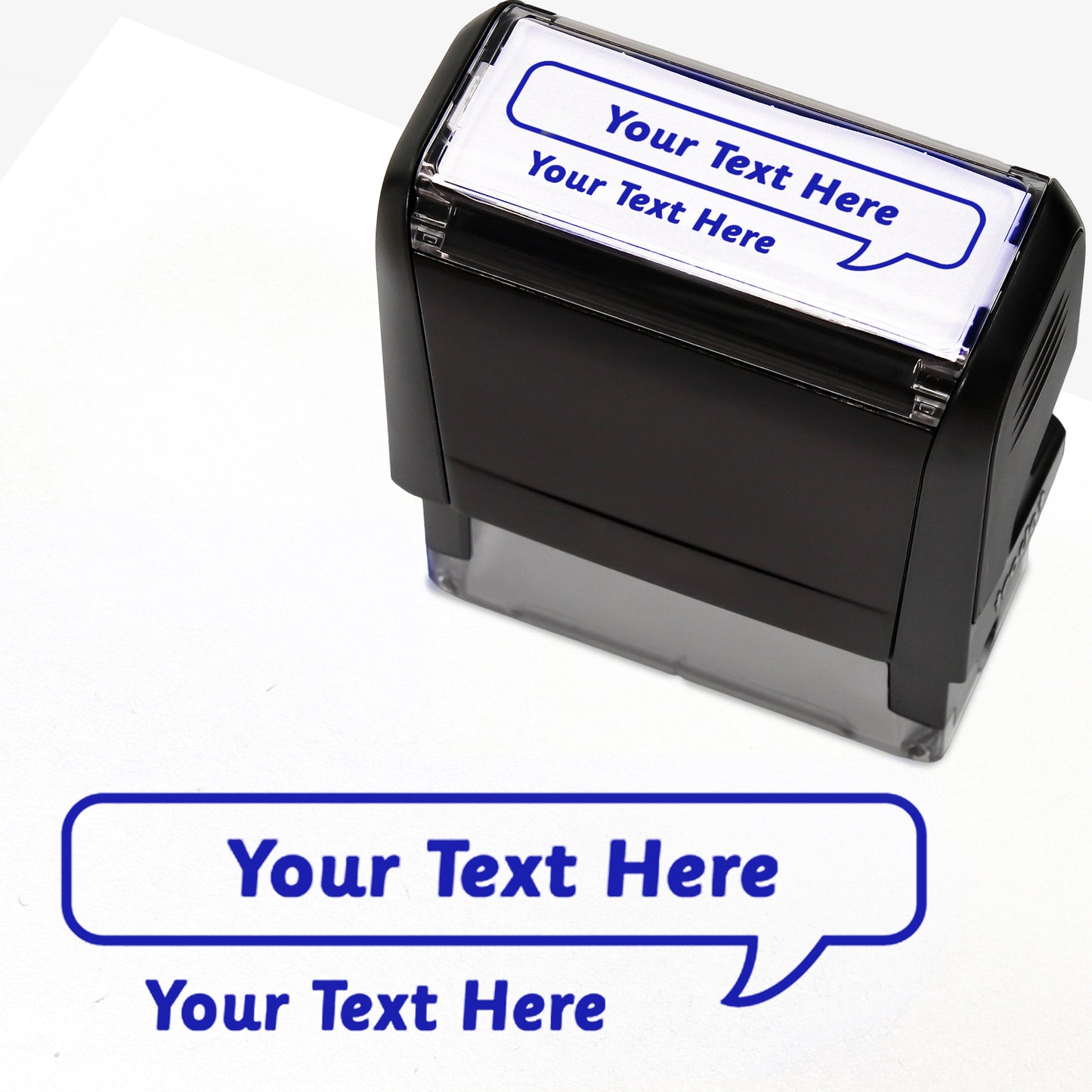 Rectangular self-inking stamper measuring 59mm by 21mm, featuring the phrase 'Your Text Here' leading onto a speech bubble going above it also saying 'Your Text Here'. In blue ink.