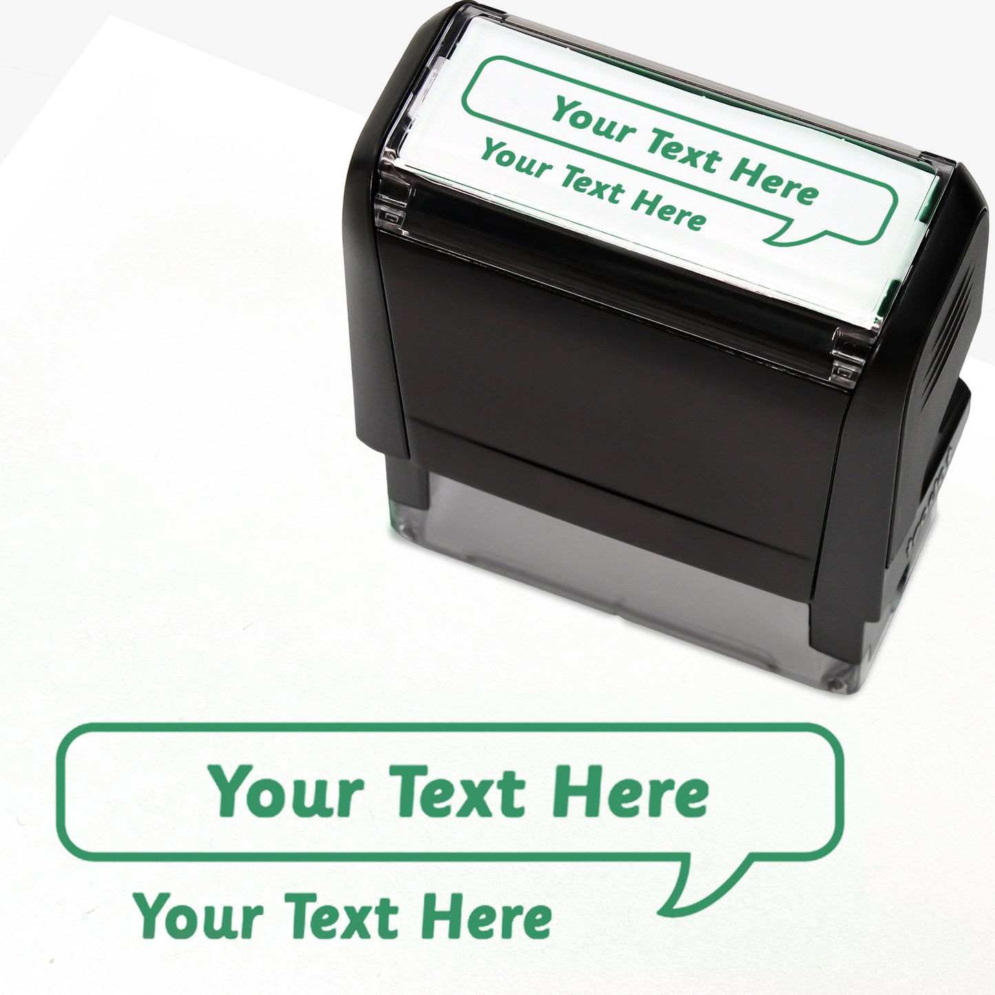 Rectangular self-inking stamper measuring 59mm by 21mm, featuring the phrase 'Your Text Here' leading onto a speech bubble going above it also saying 'Your Text Here'. In green ink.