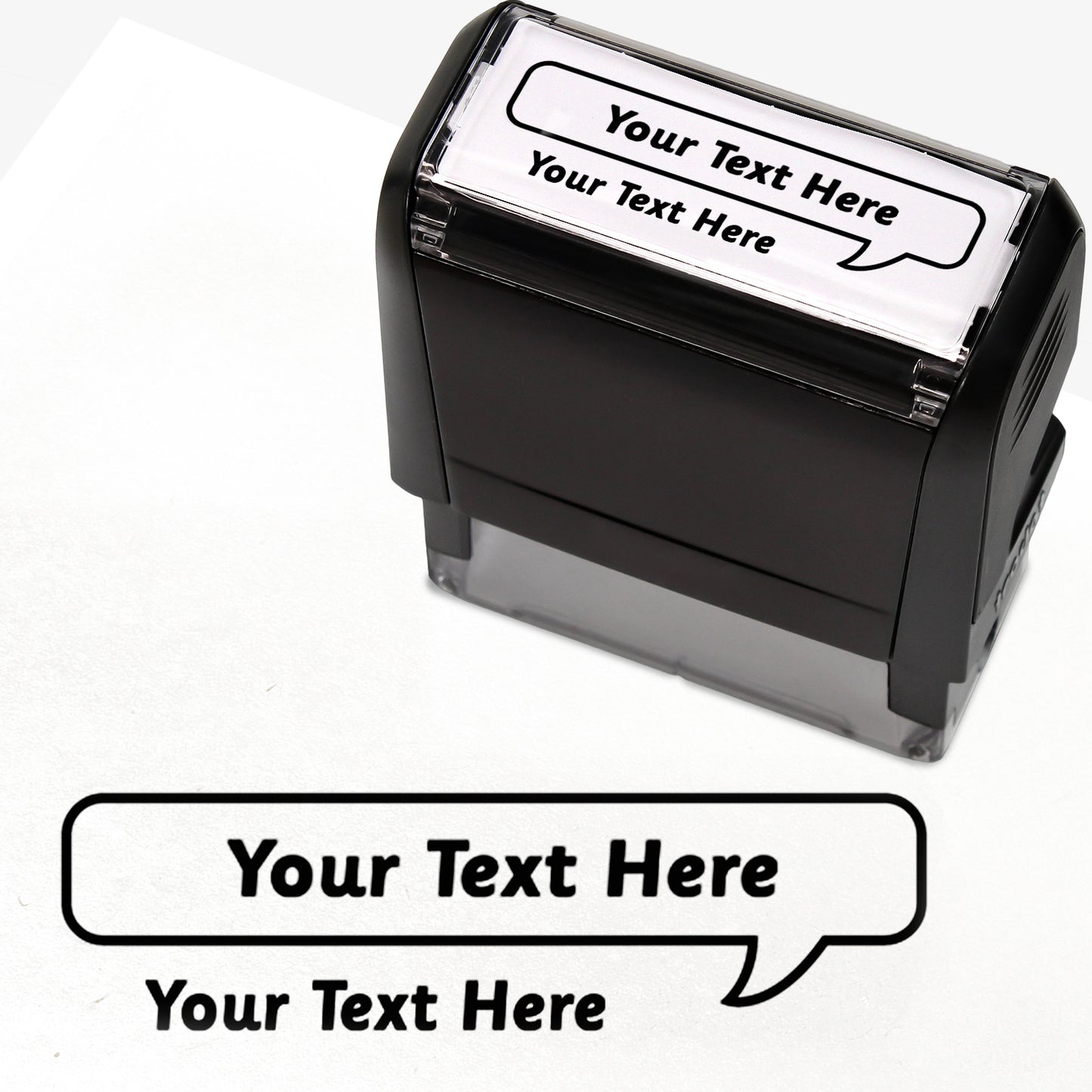Rectangular self-inking stamper measuring 59mm by 21mm, featuring the phrase 'Your Text Here' leading onto a speech bubble going above it also saying 'Your Text Here'. In black ink.