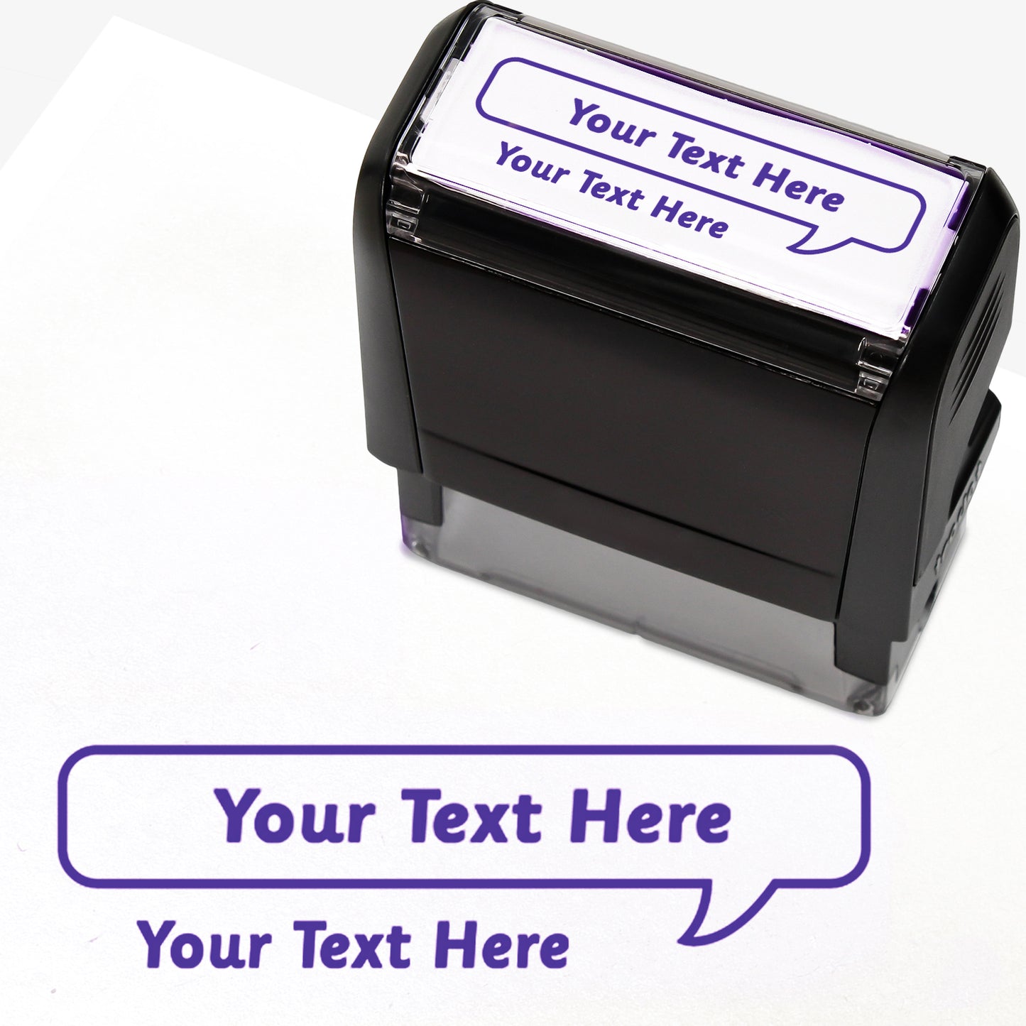 Rectangular self-inking stamper measuring 59mm by 21mm, featuring the phrase 'Your Text Here' leading onto a speech bubble going above it also saying 'Your Text Here'. In purple ink.