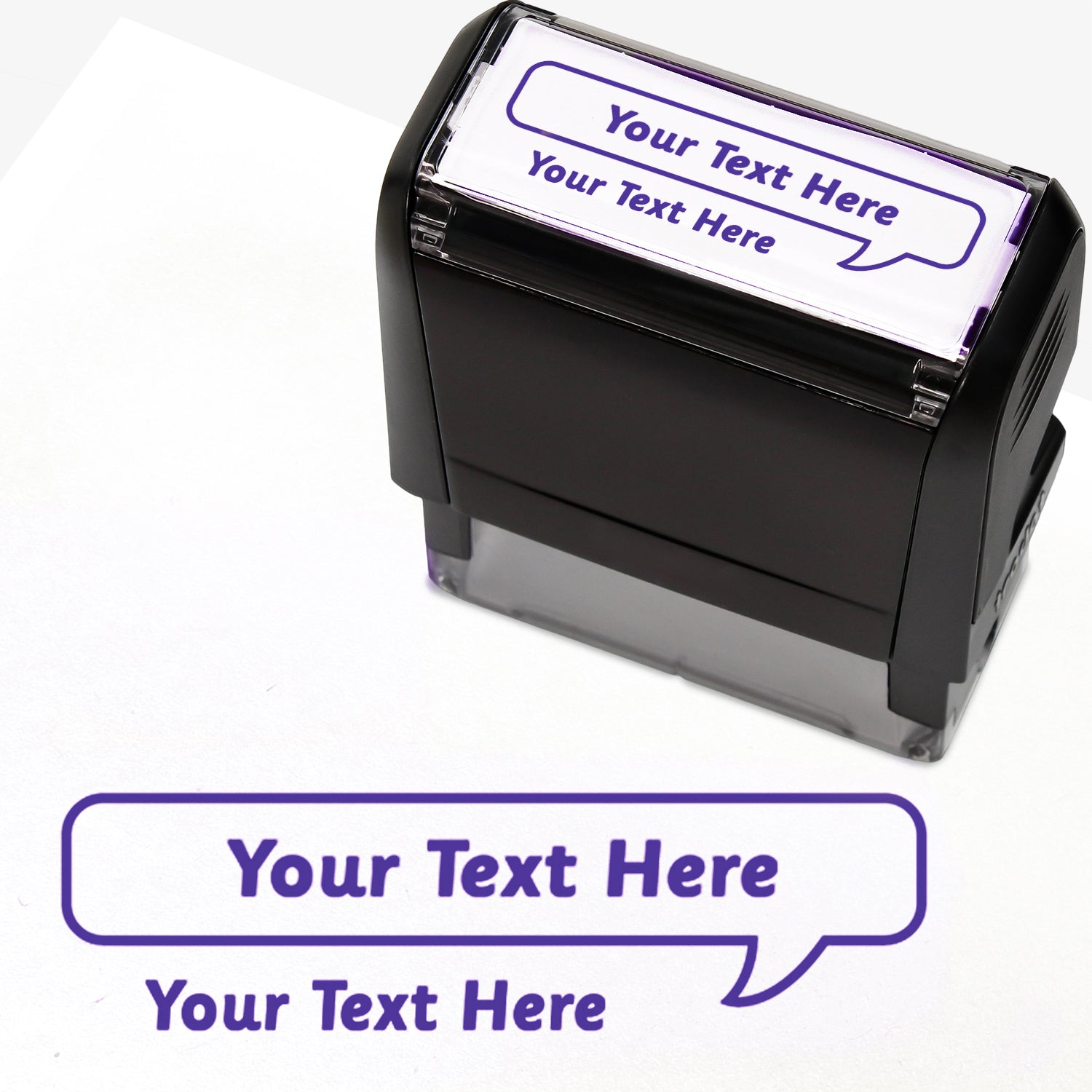 Rectangular self-inking stamper measuring 59mm by 21mm, featuring the phrase 'Your Text Here' leading onto a speech bubble going above it also saying 'Your Text Here'. In purple ink.