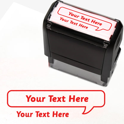 Rectangular self-inking stamper measuring 59mm by 21mm, featuring the phrase 'Your Text Here' leading onto a speech bubble going above it also saying 'Your Text Here'. In red ink.