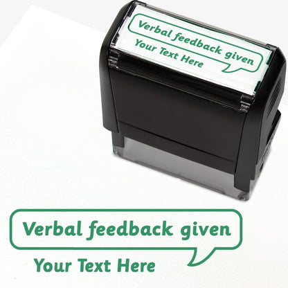 Rectangular self-inking stamper measuring 59mm by 21mm, featuring the phrase 'Your Text Here' leading onto a speech bubble going above it also saying 'Verbal Feedback Given'. In green ink.