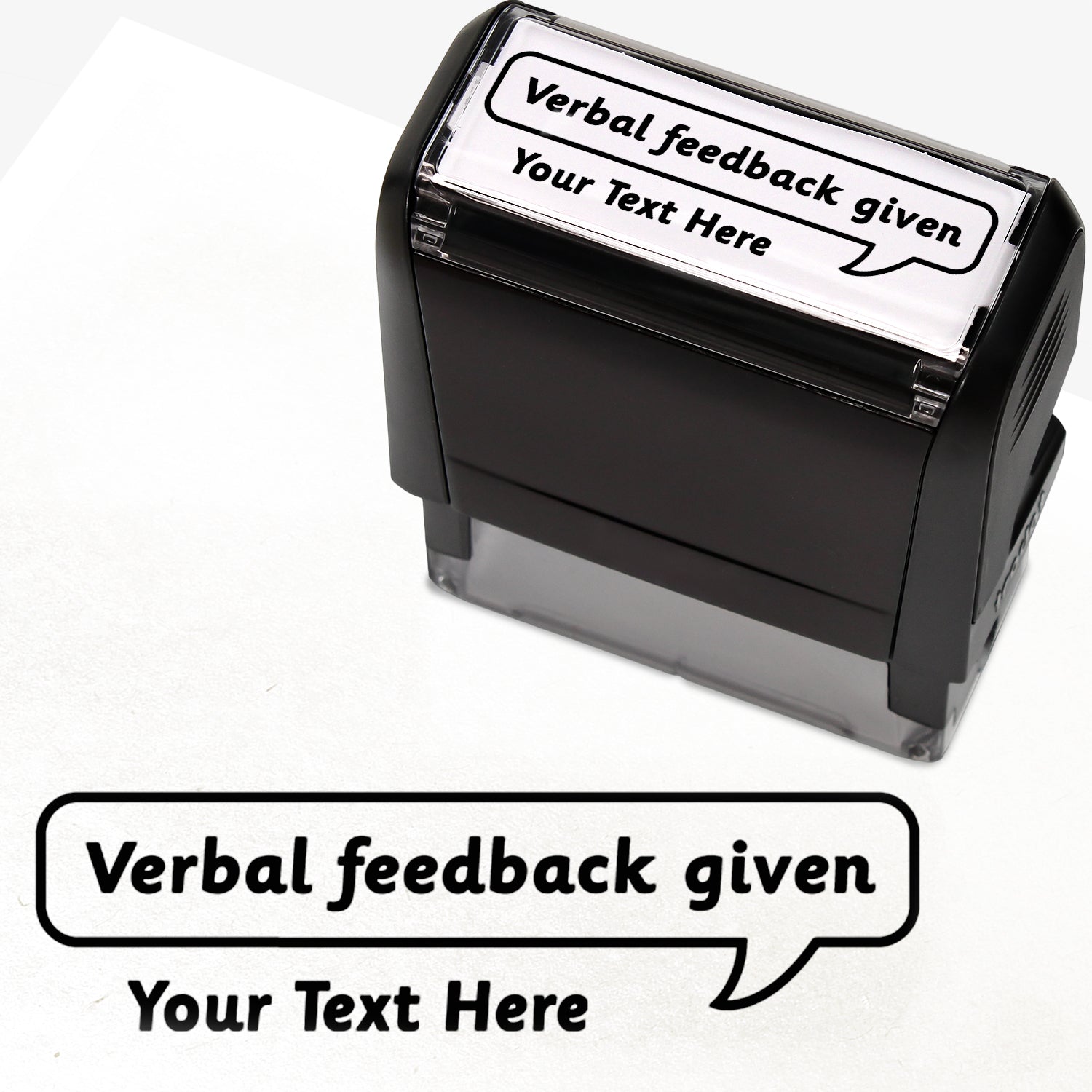 Rectangular self-inking stamper measuring 59mm by 21mm, featuring the phrase 'Your Text Here' leading onto a speech bubble going above it also saying 'Verbal Feedback Given'. In black ink.