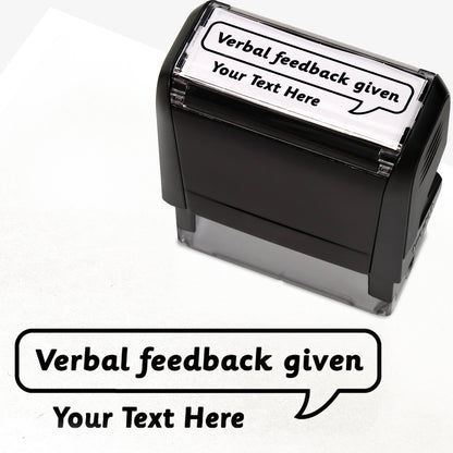 Rectangular self-inking stamper measuring 59mm by 21mm, featuring the phrase 'Your Text Here' leading onto a speech bubble going above it also saying 'Verbal Feedback Given'. In black ink.