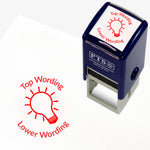 A 25mm round pre-inked teacher stamper with red ink, featuring the outline of a lightbulb, curving above the image is space for personalisation 'Top Wording' and curving below the image is space for personalisation 'Lower Wording' in a clear, bold font.