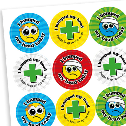 Sheet of vibrant coloured circular stickers with two main designs.  A cartoon face with a plaster or bandage on the head has text surrounding the image saying 'I bumped my head today!'; the seconf is a central first aid cross with the words 'I bumped my head today.  Please keep an eye on me' sorrounding it