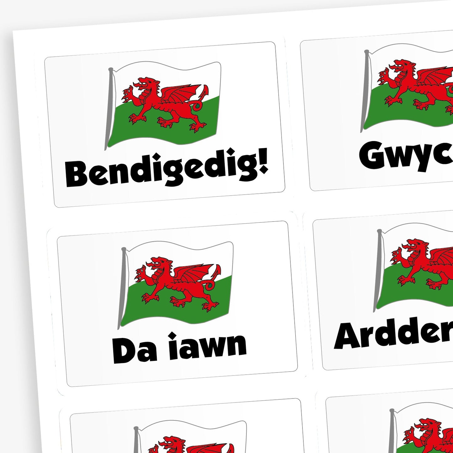 A sheet of rectangular reward stickers featuring the Welsh flag with a red dragon and positive Welsh words underneath. Phrases include 'Bendigedig!', 'Gwych', 'Da iawn', and 'Ardderchog'  all in bold black text. 