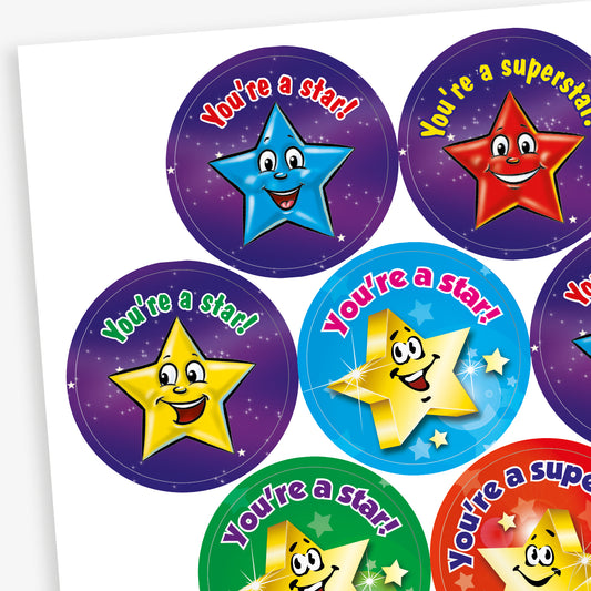 A sheet of 32mm stickers each with a cartoon, bright coloured, smiling star against a galaxy background.  Phrases inclue 'You're a star!' and 'You're a superstar'.