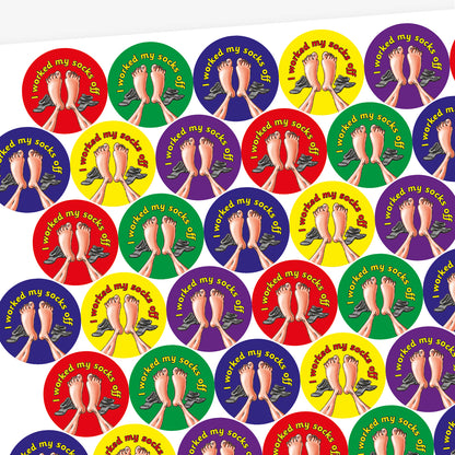 A sheet of circular stickers with clean linen scent.  Each featuring a a pair of feet with socks to the side on brightly coloured backgrounds of red, purple, yellow, blue and green.  Phrase above the image is 'I worked my socks off'