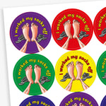 A sheet of circular stickers with clean linen scent.  Each featuring a a pair of feet with socks to the side on brightly coloured backgrounds of red, purple, yellow, blue and green.  Phrase above the image is 'I worked my socks off'